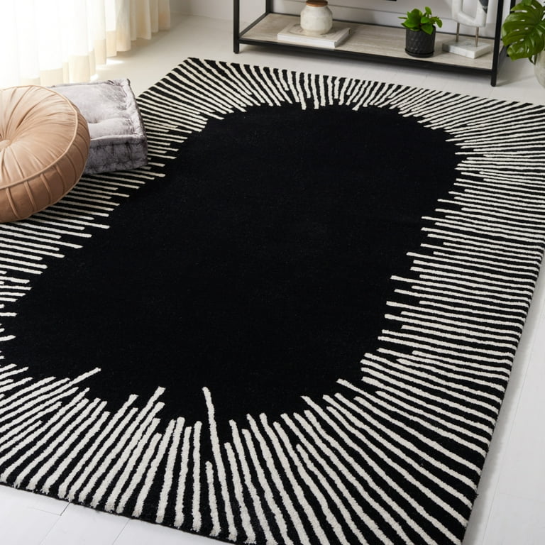 Black and white striped hand-tufted rug on a white floor with a beige pillow and plant in the background.