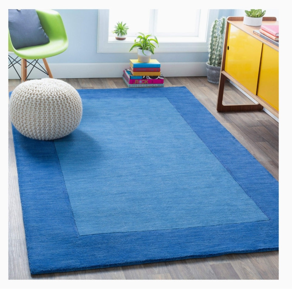 Blue hand-tufted wool area rug with tonal border in modern living room