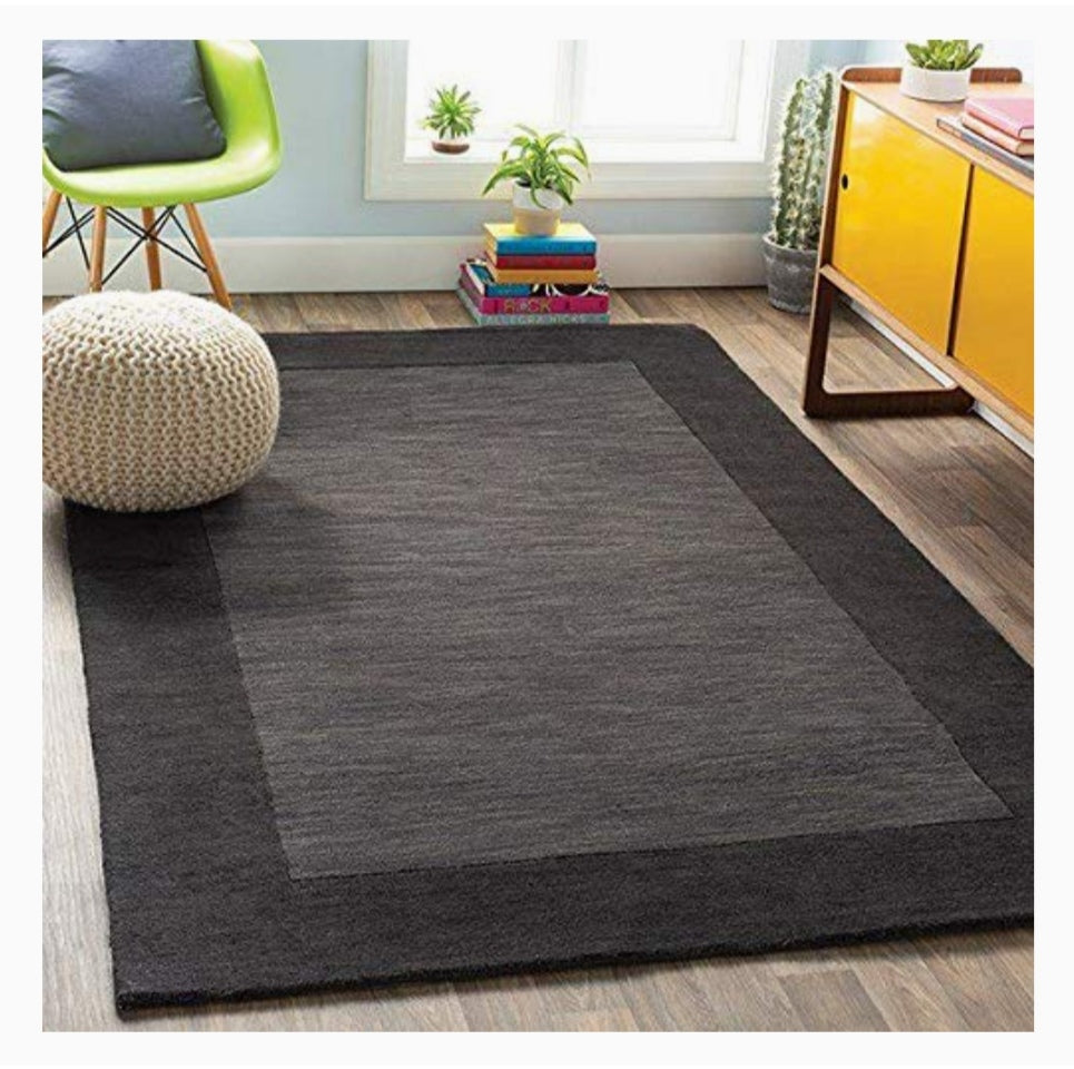 Rectangular hand-tufted wool rug with a charcoal grey border and slate grey center in a modern living room setting