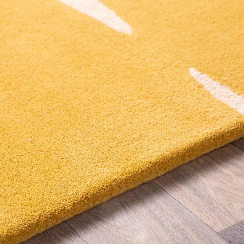 Yellow rug with white leaf patterns on a wooden floor