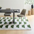 Dining area with a geometric patterned rug, chairs, and a table.