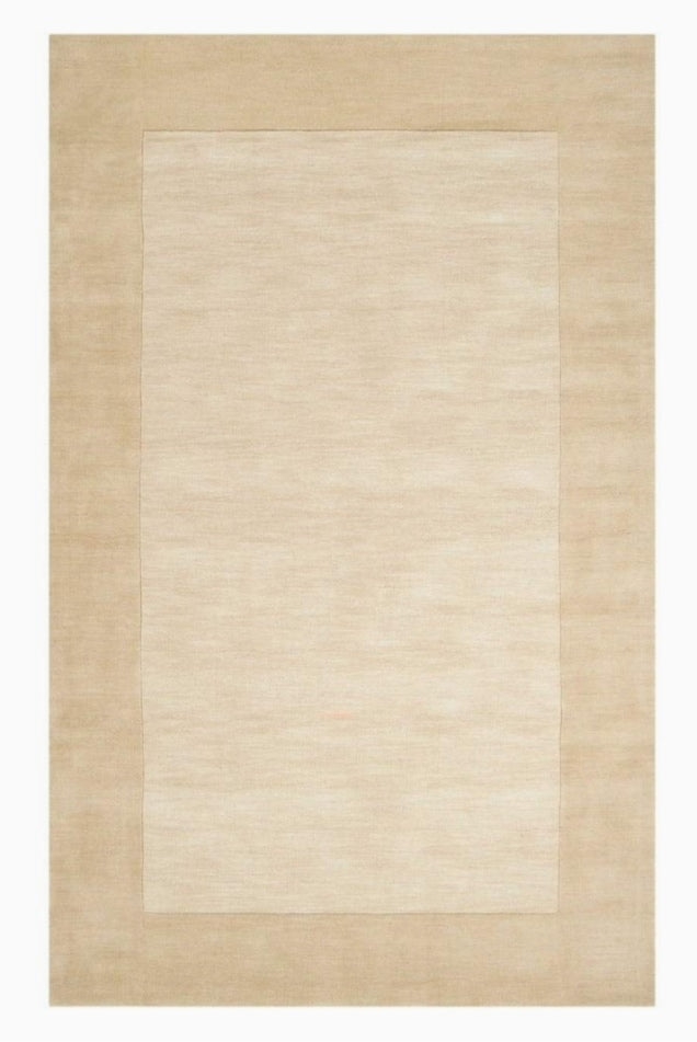 Beige area rug with a subtle pattern on a plain background