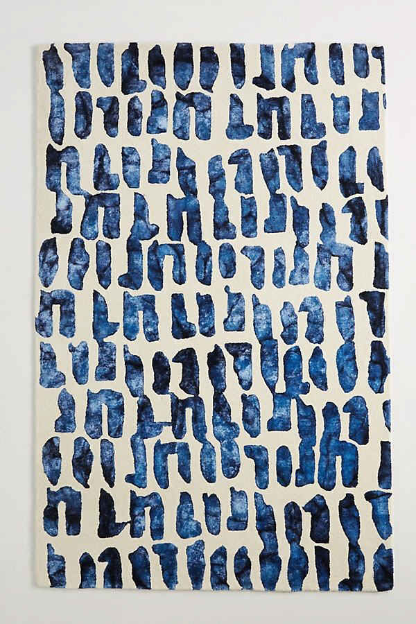 Abstract hand-tufted wool rug featuring a deep indigo brushstroke pattern on a neutral ivory background.