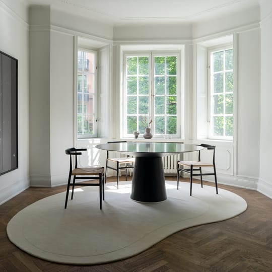 Bean-shaped hand-tufted white wool rug with minimalist curved design in a modern dining space