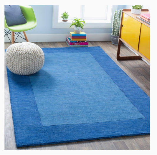 Blue hand-tufted wool area rug with tonal border in modern living room