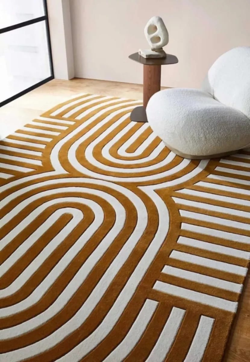 Brown and beige hand-tufted wool rug with a modern retro geometric pattern, styled with a small accent chair.