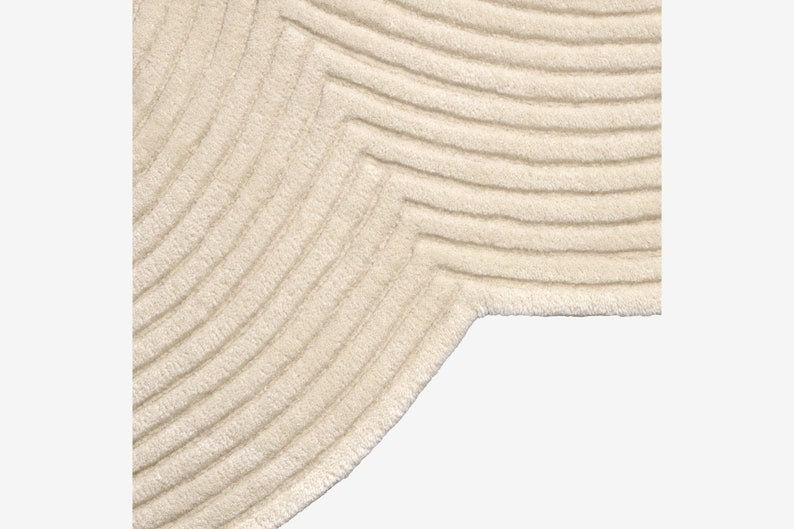Close-up of a textured beige rug with wavy pattern on a light gray background
