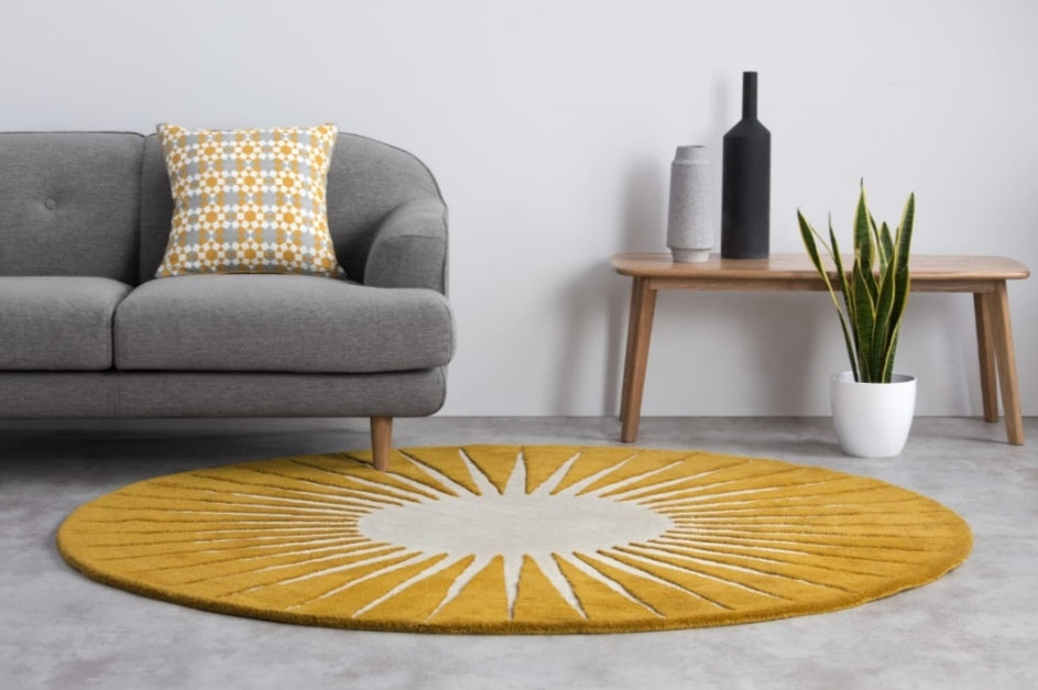 Yellow circular hand-tufted rug with a starburst design in a living room setting.