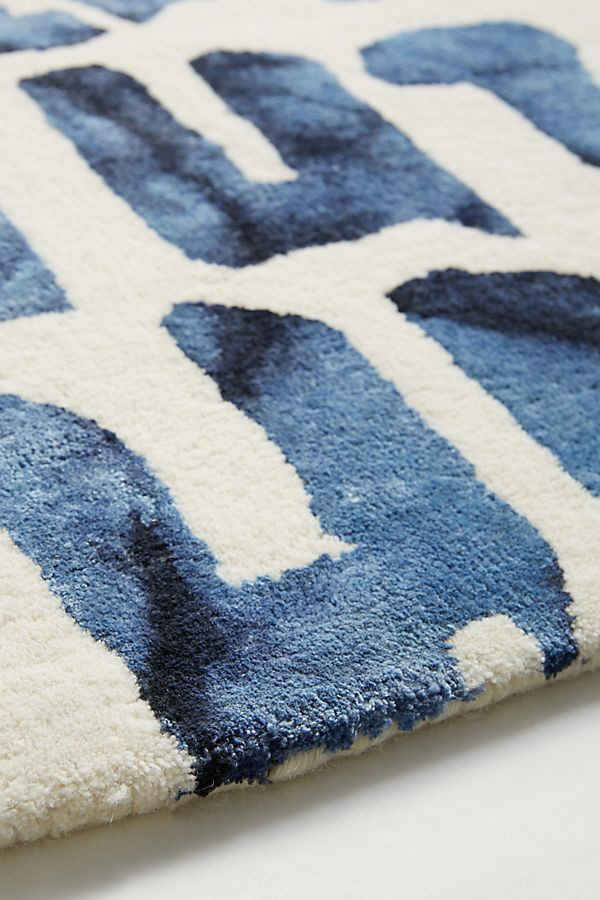 Blue and white geometric patterned rug on a plain background