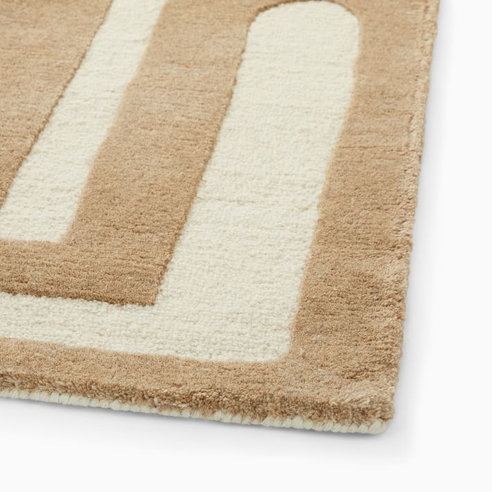 Close-up of a beige and white geometric-patterned rug corner on a white background