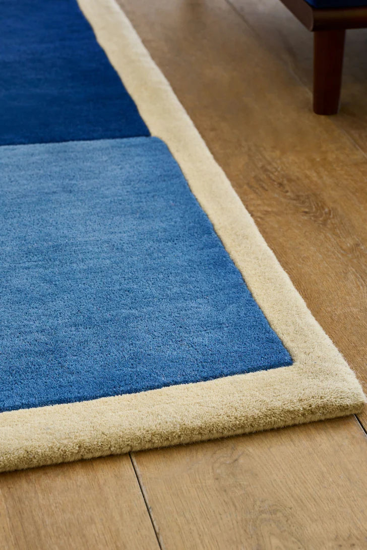 Blue rug with beige border on a wooden floor