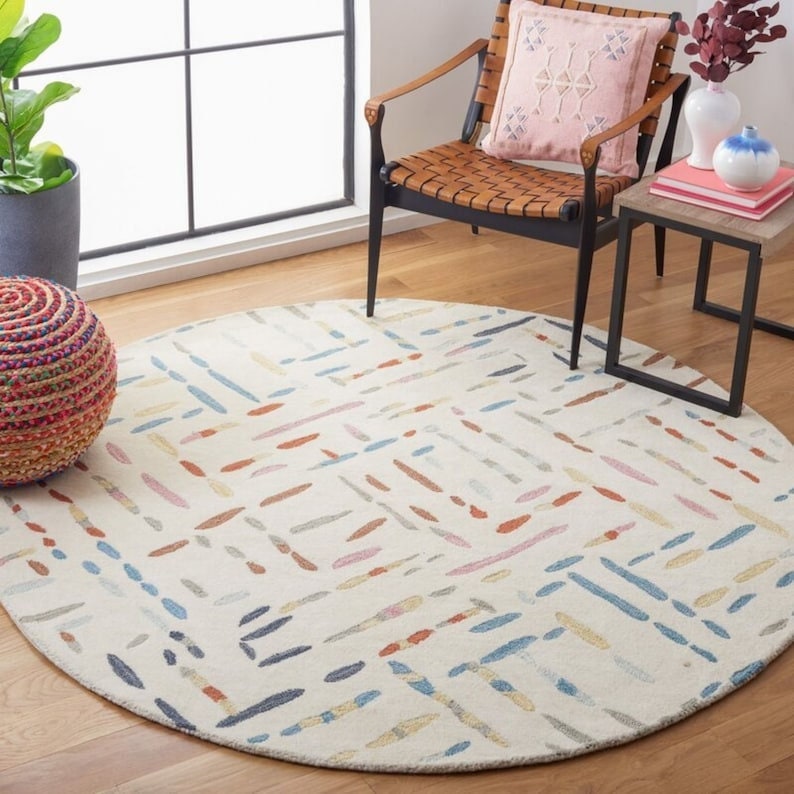 Round multicolored rug on a wooden floor with a chair and small table in the background.
