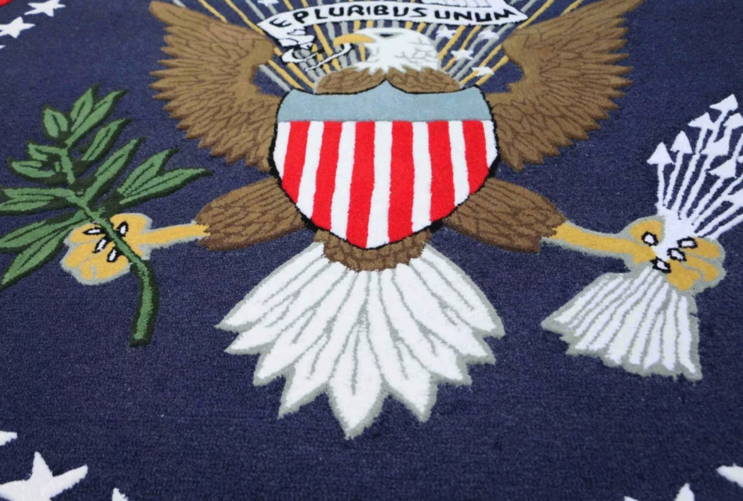 Close-up of an embroidered eagle emblem with shield and olive branch on a blue background
