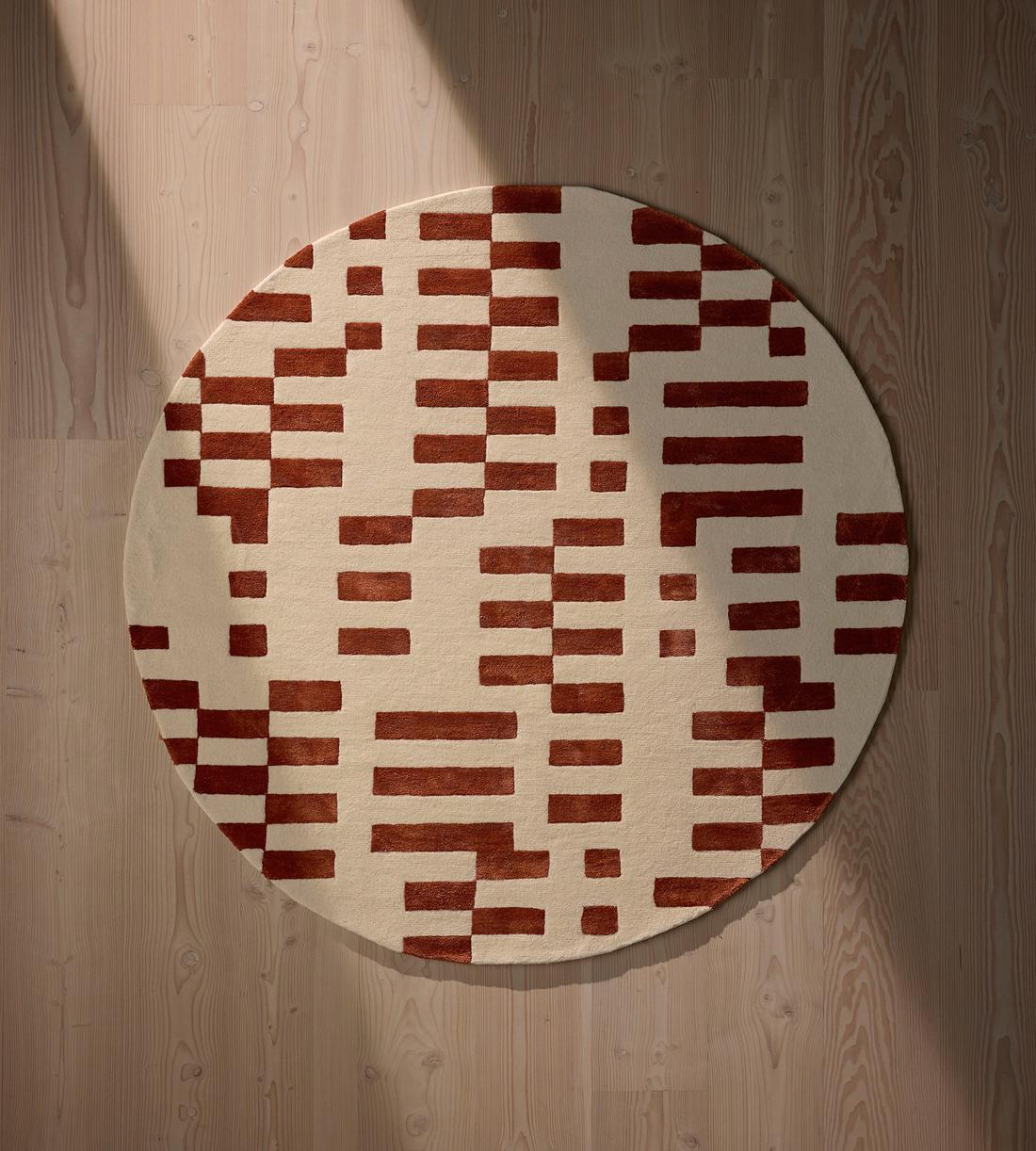 Round rug with a red and beige checkered pattern on a wooden floor