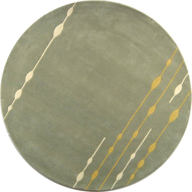 Round green rug with gold and beige geometric patterns on a white background