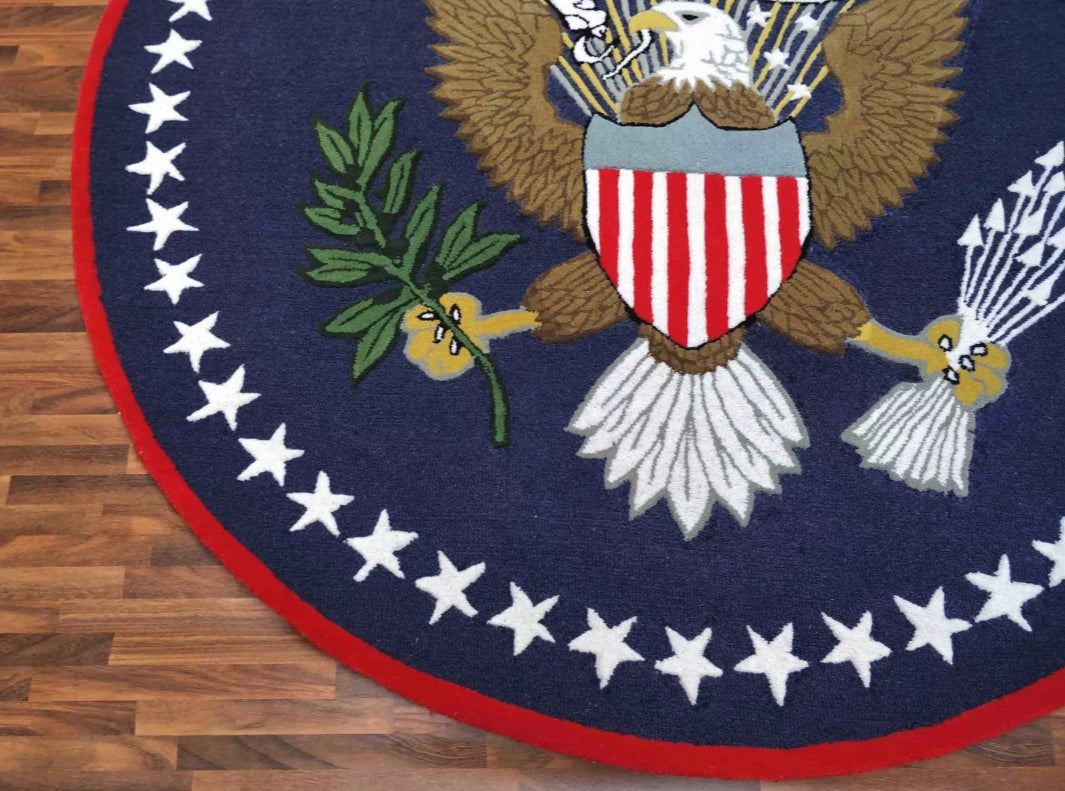 Close-up of a hand-tufted wool Presidential Seal rug showing the intricate detail of the eagle's feathers, olive branch, and white stars on navy wool.